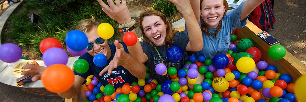 Three students spend time together in a ball pit.